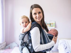 Babywearing: una mamma porta i suoi due bambini sulla schiena e sul petto grazie ai supporti per il babywearing