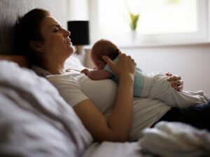 Il post parto: una mamma riposa tenendo al petto il proprio neonato