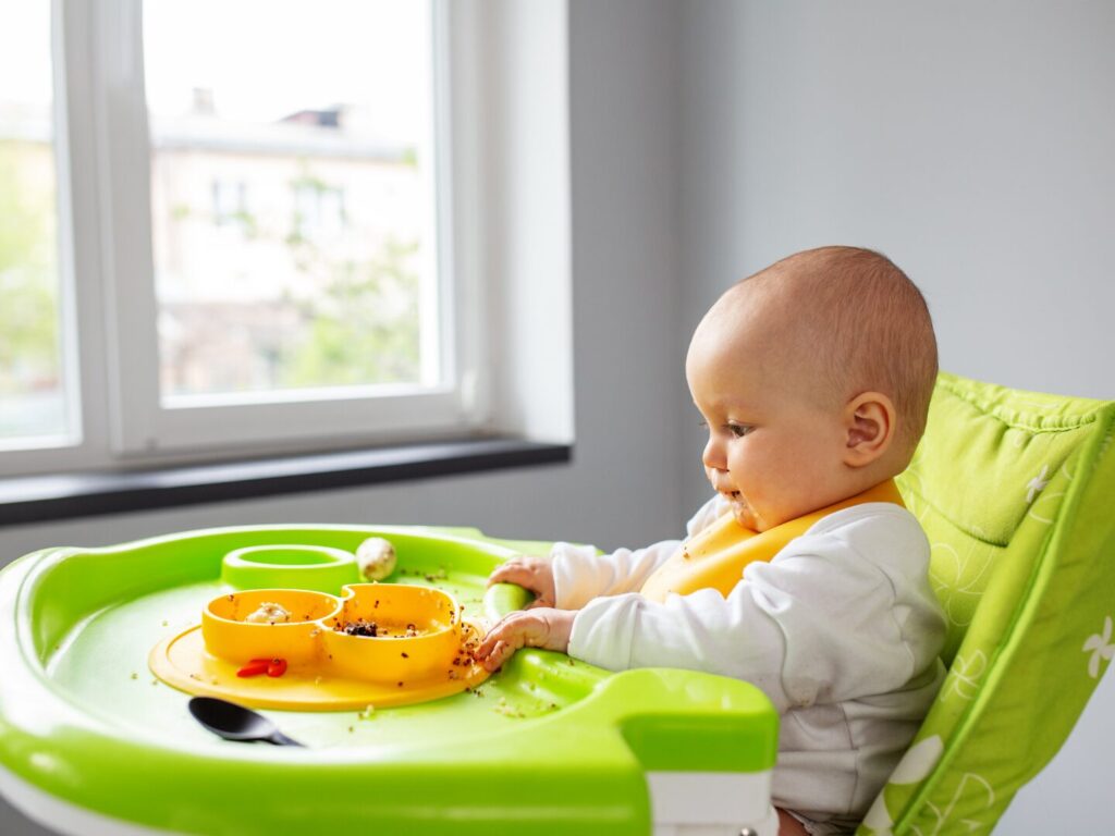 Lancio del cibo: un neonato osserva il piatto di fronte a sé